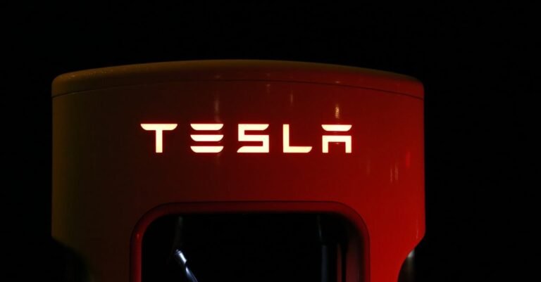 Close-up of a Tesla charging station illuminated at night, showcasing modern automotive technology.