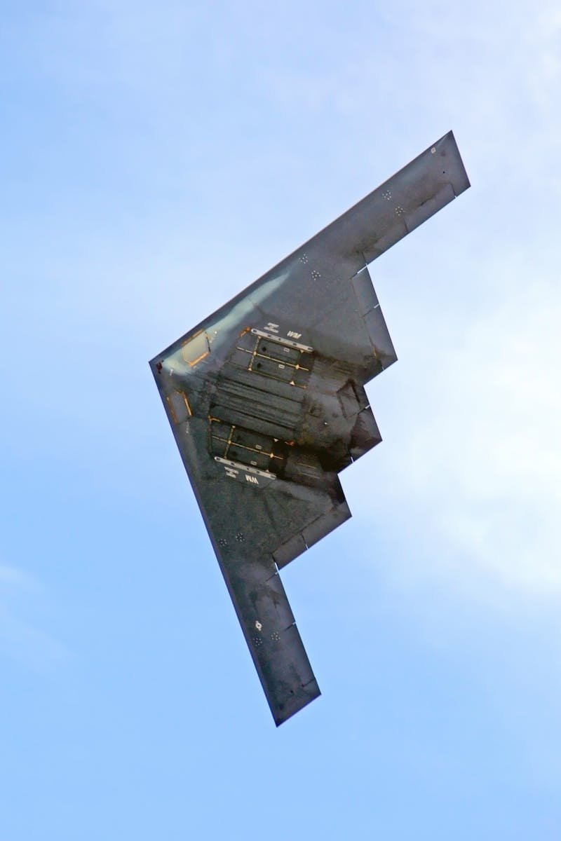 A sleek stealth bomber soars through a clear blue sky, showcasing advanced military aviation.
