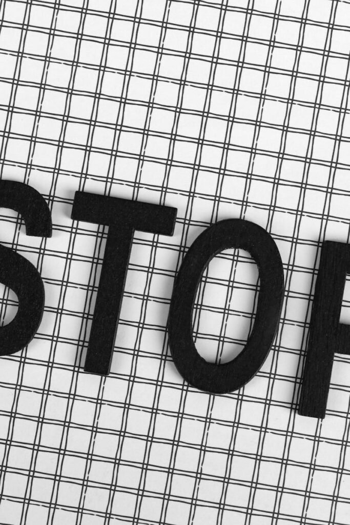 Black wooden letters spelling 'STOP' on a black and white grid background.