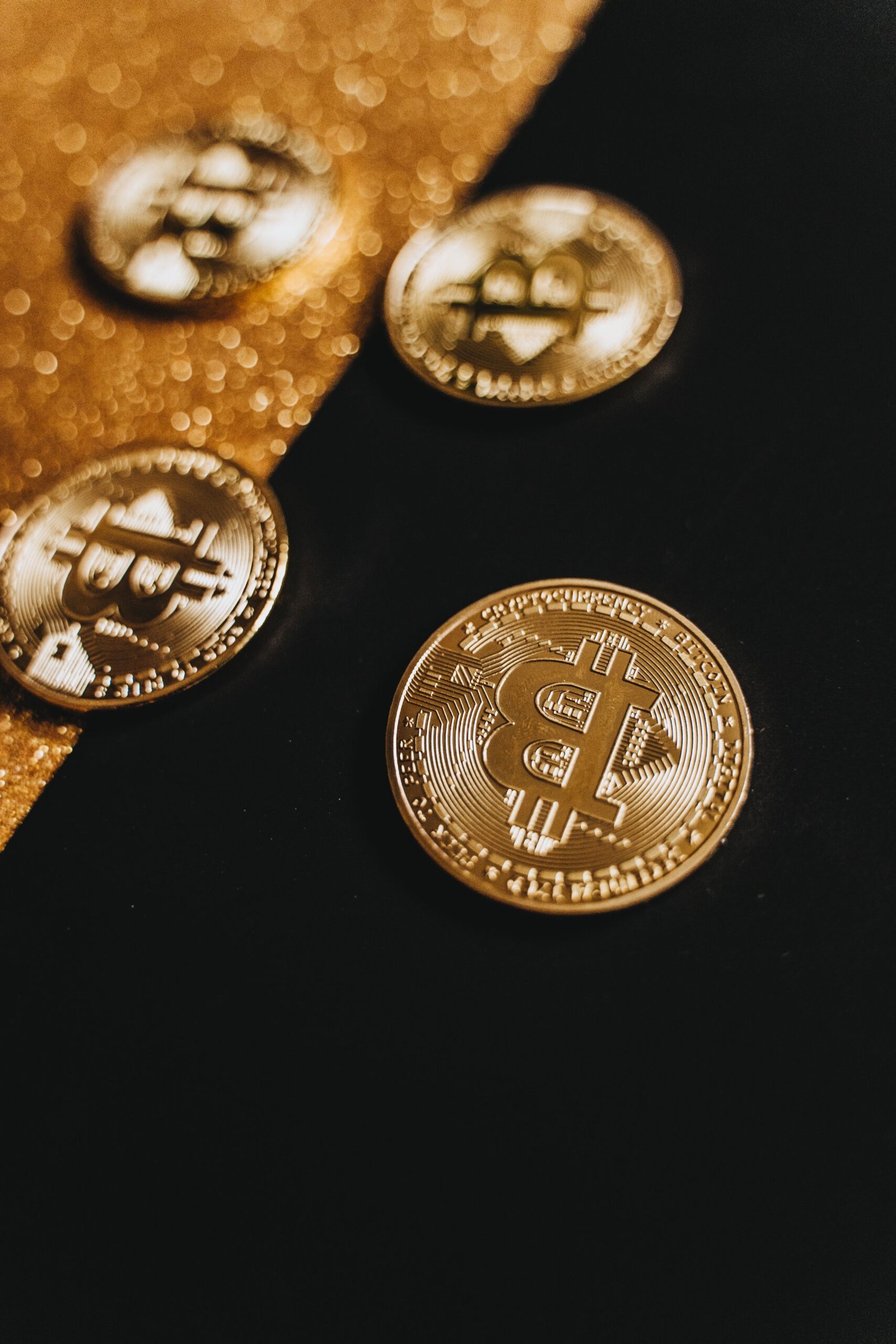 A stylish close-up of gleaming Bitcoin coins on a contrasting black and gold background.