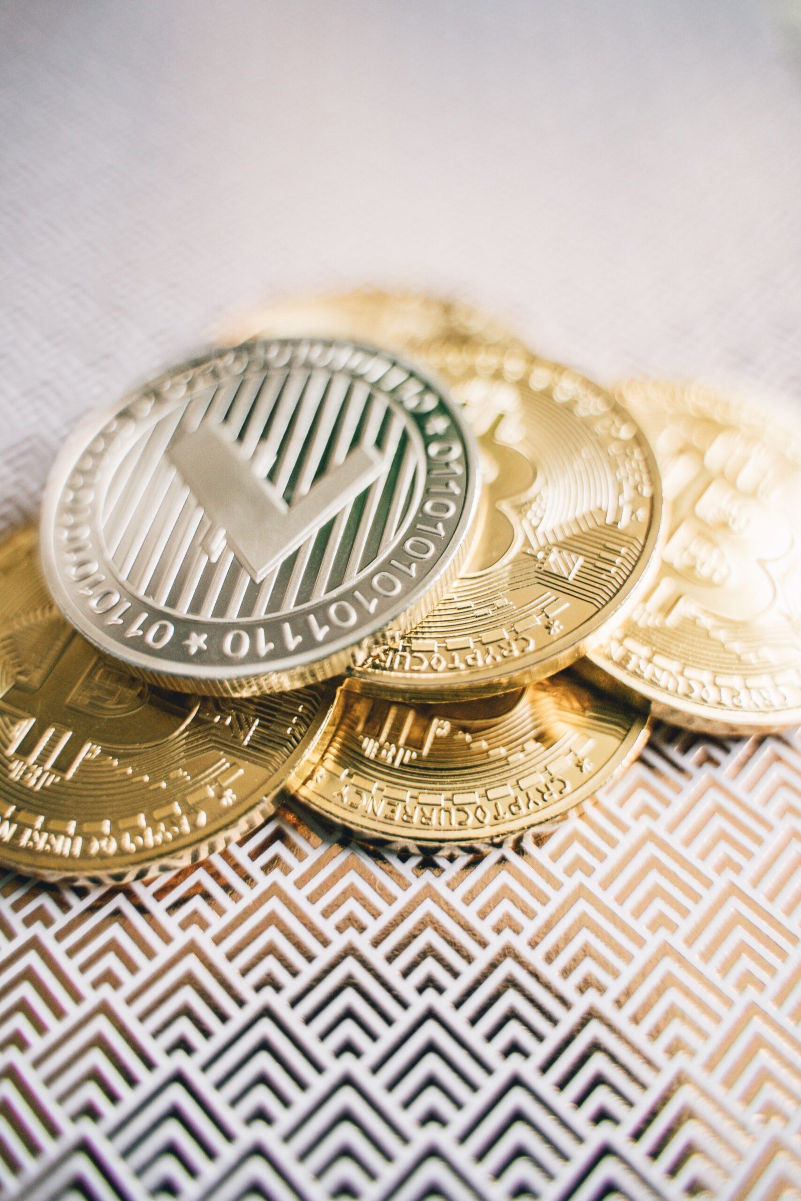 Detailed view of gold and silver cryptocurrency coins on a geometric patterned surface.